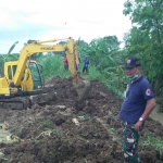 Petugas BPBD Lamongan berusaha membendung tanggul yang jebol. (foto: ist)