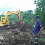 Petugas BPBD Lamongan berusaha membendung tanggul yang jebol. (foto: ist)