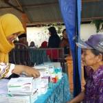 Salah satu anggota binaan Baznas dari Kel. Merjosari sedang mengambil obat sambil menyimak penjelasan dari petugas. foto: iwan irawan/ BANGSAONLINE