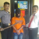 Tersangka Suyatno beserta barang bukti pedang didampingi petugas polsek Porong. 