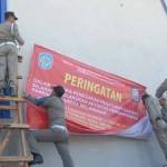 DISEGEL – Petugas Satpol PP memasang tanda segel di pabrik PT Mitra Saruta, karena belum ber-IMB, Kamis (20/8). foto: soewandito/BANGSAONLINE