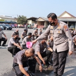 Kapolres Kediri AKBP Agung Setyo Nugroho saat menguyur air kembang kepada salah satu personel yang naik pangkat. foto: ist.