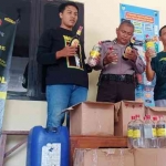 Petugas Polsek Wates saat menunjukkan barang bukti berupa 77 botol miras dan 2 jirigen arak. Foto: Ist.