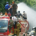 Petugas menyemprotkan disinfektan ke jalanan menggunakan mobil damkar.