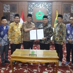 Pj Bupati Pamekasan bersama anggota KPU saat menunjukkan NPHD yang telah ditandatangani.
