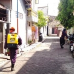 Petugas melakukan penyemprotan disinfektan di depan rumah warga yang sepi lantaran kebijakan pemerintah yang menerapkan stay at home. foto: SYUHUD/ BANGSAONLINE