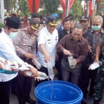 Bupati Sambari bersama pejabat Forkopimda ketika menuangkan miras ke dalam drum untuk dimusnahkan. foto: SYUHUD/ BANGSAONLINE