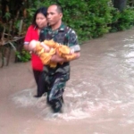 Sertu Juhartono, anggota Babinsa yang bertugas di Koramil 09/Saradan menggendong bayi.