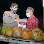 Kapolresta Sidoarjo Kombes Pol. Kusumo Wahyu Bintoro membagikan bantuan sosial paket sembako kepada penjual kelapa muda.