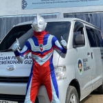 Petugas SPPG Yayasan Tarbiyatul Mubtadiin Pakong, berkostum ultraman berdiri di depan mobil SPPG