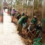 Ibu-ibu yang memakai topi caping bersemangat ikut membantu kerja Satgas TMMD.