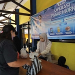 Petugas saat melayani warga yang sedang antri berbelanja. (Ist)