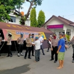 Kapolres Kota Kediri, AKBP Miko Indrayana saat menyerahkan nasi kotak hasil masakan dapur umum kepada abang becak. 