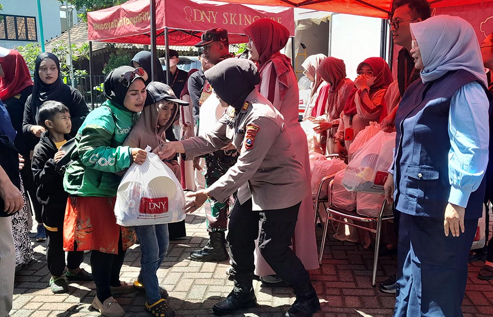 Anggota polisi ikut membantu pembagian bingkisan DNY Skincare, Sabtu (14/3/2026). Foto: MUSTAIN/ BANGSAONLINE