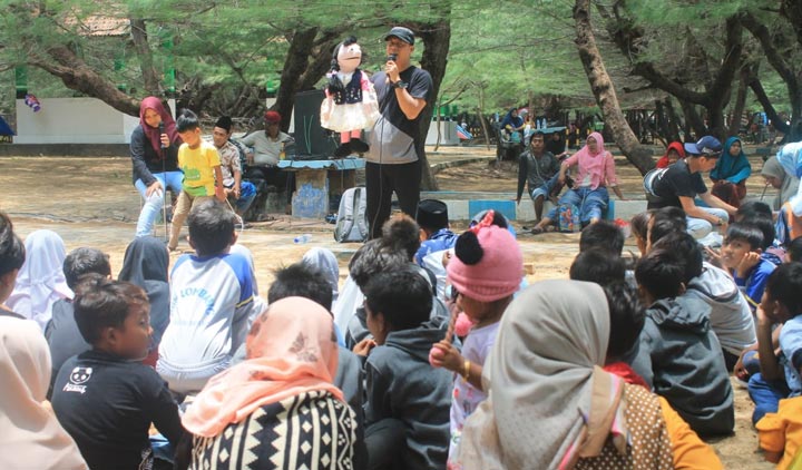 Kak Avan, Relawan Rumah Cerita OKARA saat membawakan dongeng di Pantai Lombang.