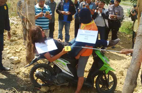 Salah satu adegan yang diperagakan tersangka pada korban yang diperankan oleh anggota Polres Lamongan. (foto: haris/BANGSAONLINE)