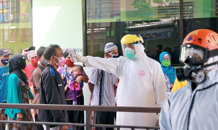 Petugas saat memeriksa suhu badan warga yang antre sebelum menjalani rapid test. foto: ist