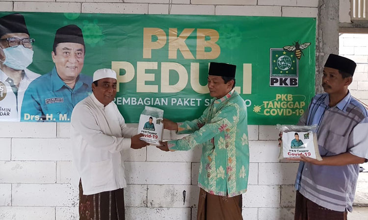 KH. Drs. M. Jamhuri menyerahkan sumbangan sembako dan masker kepada salah satu tokoh masyarakat Arosbaya, Ustadz Farosdad.