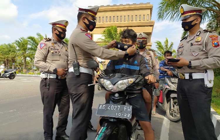 Kasatlantas Polres Kediri AKP Bobby Mochamad Zulfikar saat memakaikan masker kepada pengguna jalan yang kedapatan tidak pakai masker. (foto: ist.)
