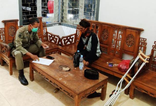 Herman Jaya saat dimintai keterangan oleh petugas Satpol PP Kota Kediri. Dia ingin tetap berjalan kaki pakai krek keliling Indonesia. (foto: Istimewa)

