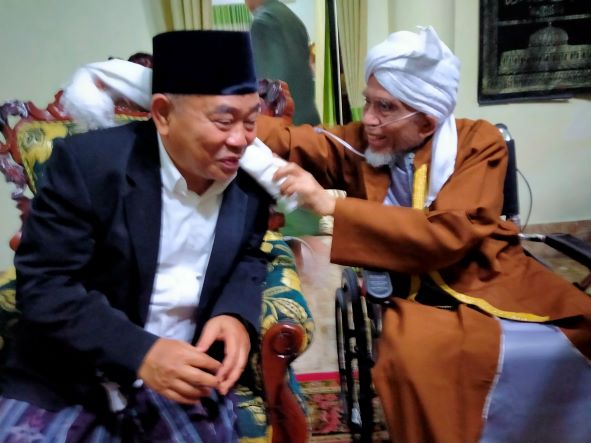Tuan Guru Haji (TGH) Lalu Turmudzi Badaruddin mengalungkan sorban kepada Prof Dr KH Asep Saifuddin Chalim, MA di  Pondok Pesantren Qomarul Huda, Bagu, Lombok Tengah NTB , Rabu (13/10/2021). foto: mma/ bangsaonline.com