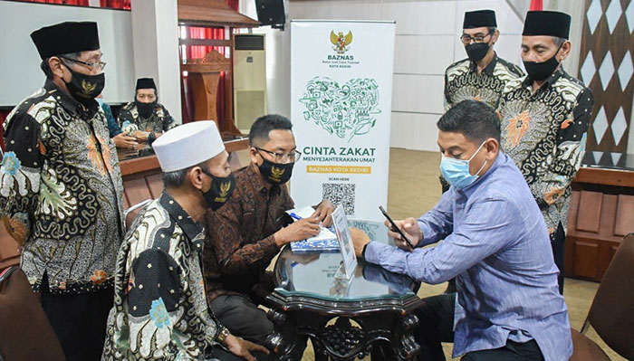 Wali Kota Kediri, Abdullah Abu Bakar (duduk kanan), saat didampingi pengurus Baznas Kota Kediri saat menyaluran zakat dengan cara scan QRIS. Foto: Ist