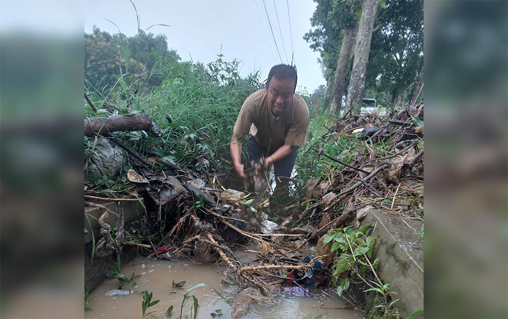 Wakil Bupati Magetan Kang Suyat turun langsung membersihkan sumbatan sampah di selokan saat meninjau banjir di Ngariboyo. Foto: ANTON/HB