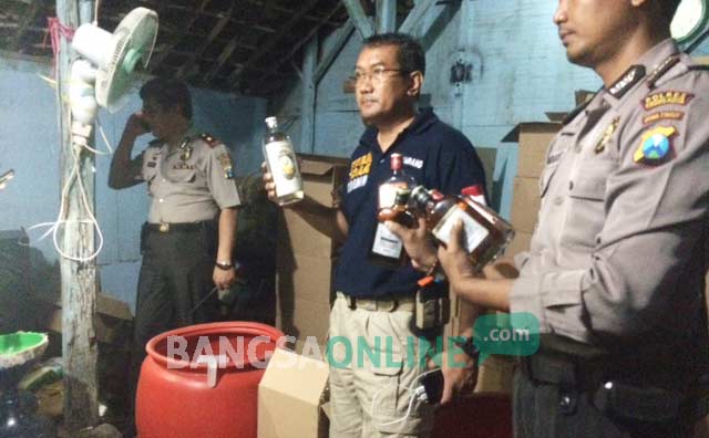 Petugas kepolisian saat menggerebek rumah yang memproduksi minuman keras ilegal di kelurahan Setono Pande Kota Kediri. foto: arif kurniawan/ BANGSAONLINE