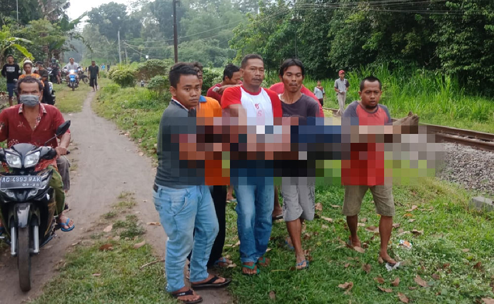 Suami dari korban yang ditemukan dalam kondisi terluka parah sedang digotong oleh warga untuk dibawa ke rumah sakit.