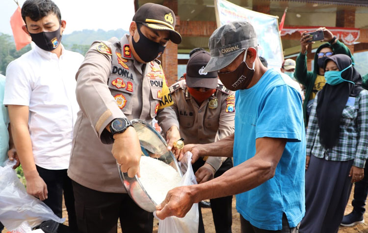 Kapolres Mojokerto AKBP Dony Alexander ikut membagikan langsung bantuan beras ke masyarakat.