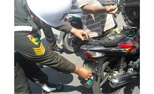 Petugas saat mencopot stiker bergambar atribut TNI dari sepeda motor milik warga. foto: dendi martoni/BANGSAONLINE