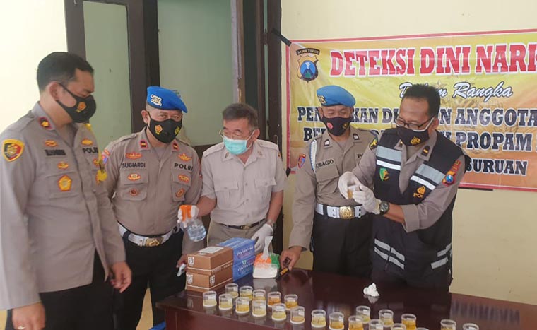 Wakapolres Pasuruan Kompol Muhammad Harris (kiri) didampingi Kasi Propam Ipda Sugihardi saat menyerahkan urineya di Halaman Gedung Panaluan Mapolres Pasuruan. foto: ANDY F/ BANGSAONLINE
