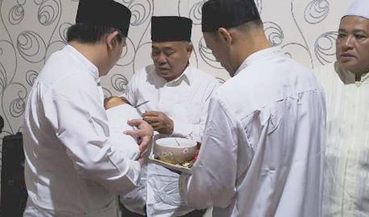 Dr. KH. Asep Saifuddin Chalim, MA saat memotong rambut Abdul Hakim, cucunya yang ke-10, dalam acara istighotsah aqiqah.  Tampak Abdul Hakim, digendong oleh sang ayah Muhammad Habibur Rohman (Gus Habib).