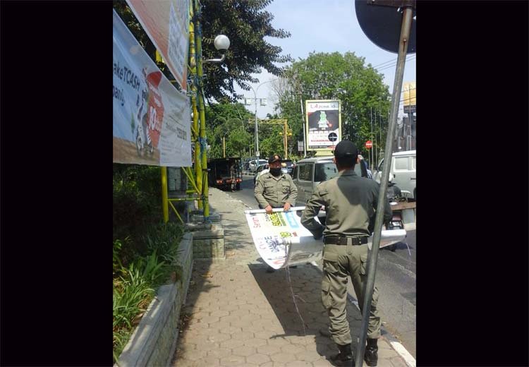 Petugas Dispol PP ketika mencopot spanduk liar di salah satu titik jalan protokol.