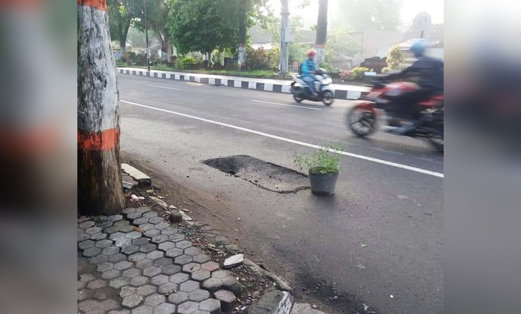 Kerusakan jalan di jalan Empunala oleh warga diberikan tanda pot. 