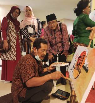 Drs. Romadlon Sukardi (jongkok pakai kopiah hitam) menyaksikan salah satu seniman yang sedang mendemonstrasikan kebolehannya dalam melukis. foto: ist