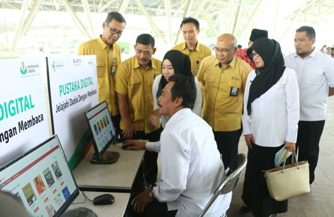 Wabup Moh. Qosim didampingi Sekretaris Perusahaan PG Wahyudi saat mencoba perpustakaan digital. foto: SYUHUD/ BANGSAONLINE