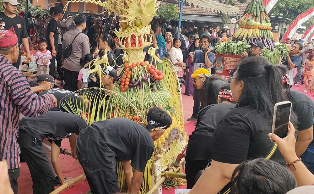 Dua tumpeng besar berisi hasil bumi dan buah-buahan diarak sebelum diperebutkan warga. Foto: MUJI HARJITA/ BANGSAONLINE