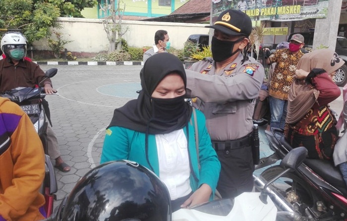 Kapolsek Ngadiluwih AKP Mukhlason, S.H. sedang memakaikan masker kepada salah satu pengguna jalan. foto: ist.
