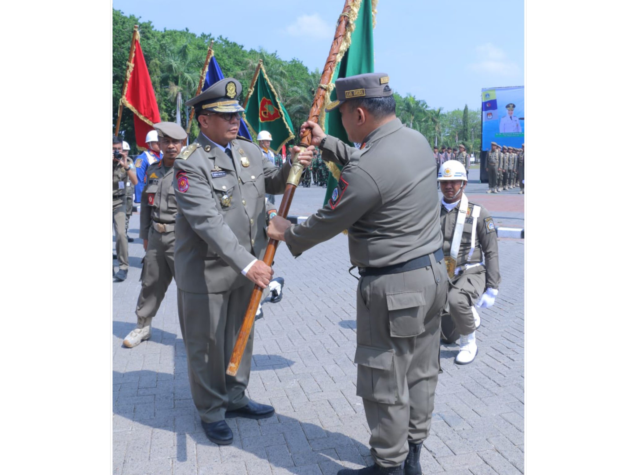 Kepala Satpol PP Gresik, Agustin Halomoan Sinaga (kanan) menyerahkan bendera pataka kepada Sekda Achmad Washil Miftahul Rachman. Foto: Ist.