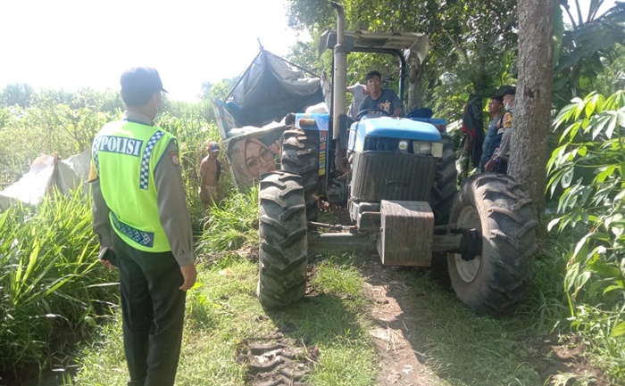 Truk pengangkut beras yang nyelonong ke jalan makam desa sedang dievakuasi menggunakan traktor. foto: ist.