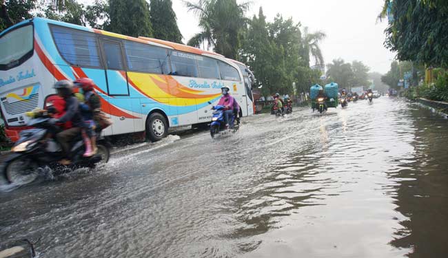 Kendaraan bus ini bergerak lambat akibat genangan banjir, setelah diguyur hujan deras Jumat malam. (ft: rony suhartomo/ BANGSAONLINE)