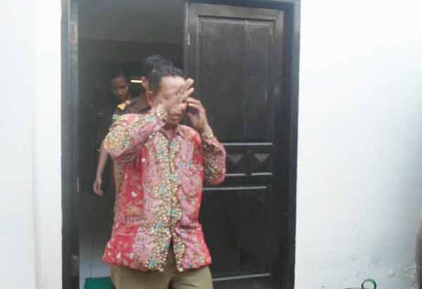 Tersangka korupsi bansos sapi,  Abdul Kodim hanya tersenyum kecut ketika digelandang petugas untuk menuju tahanan, kemarin. foto : catur andy/BANGSAONLINE