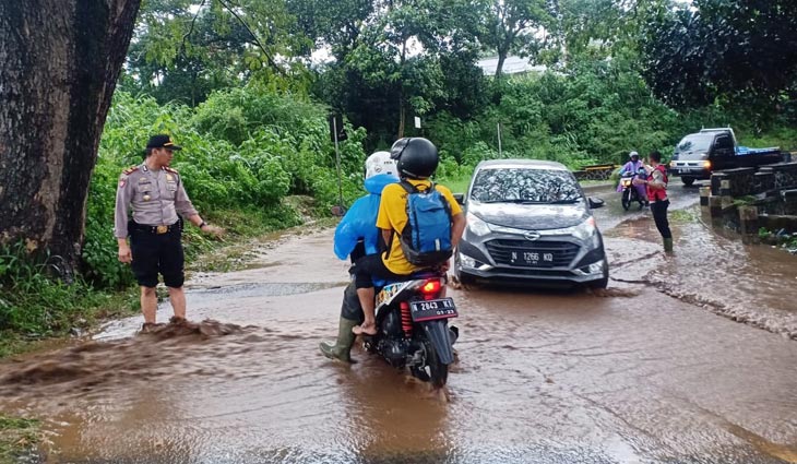 Akibat hujan deras, jalan Raya Tlekung-Oro-oro Ombo banjir. Tampak petugas Satsabhara Polres Batu mengatur arus lalu lintas.