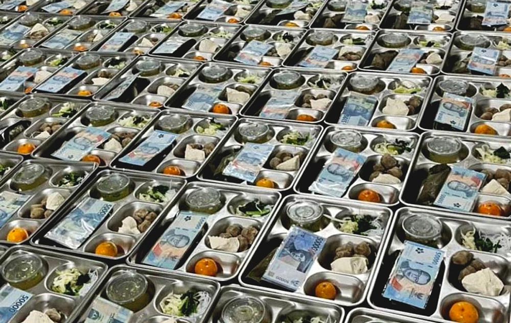 Uang pecahan Rp50.000 tampak terselip di atas ompreng menu MBG yang dibagikan untuk sejumlah sekolah di Bangkalan.