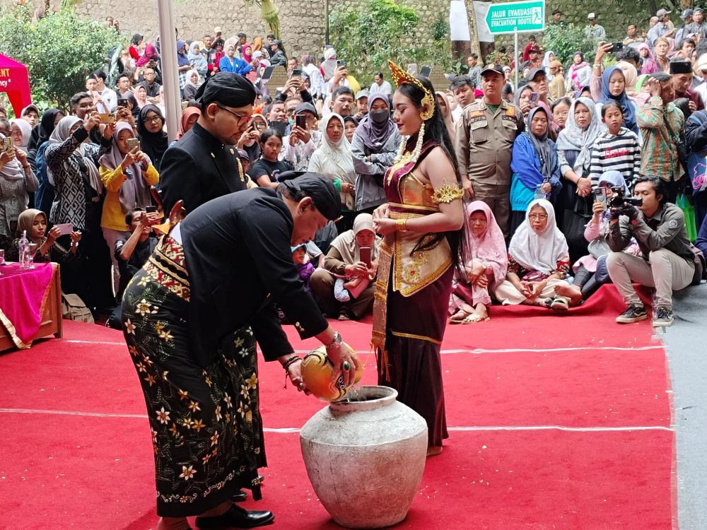 Bupati Nganjuk, Marhaen Djumadi saat mengambil air yang dibawakan gadis dari air terjun Sedudo. Foto: Bambang Dwi Julianto/BANGSAONLINE