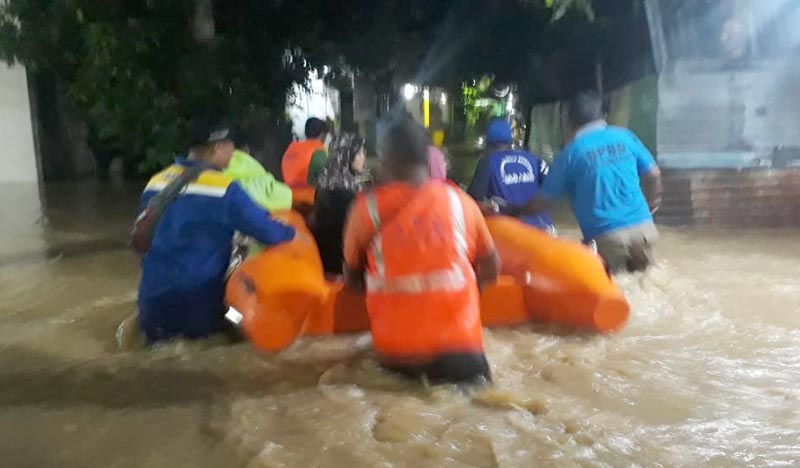 Petugas BPBD dan Tagana mengevakuasi warga beserta barang-barang menggunakan perahu karet.