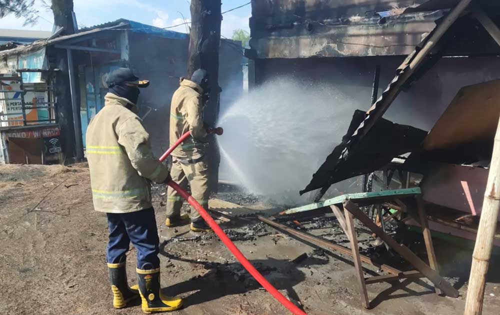 Petugas Damkar Gresik saat melakukan pembasahan terhadap warkop yang terbakar. Foto: Ist.