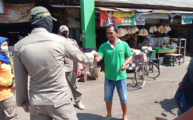 Petugas Satpol PP Kota Kediri saat memberikan masker kepada pengunjung pasar. (foto: ist.)