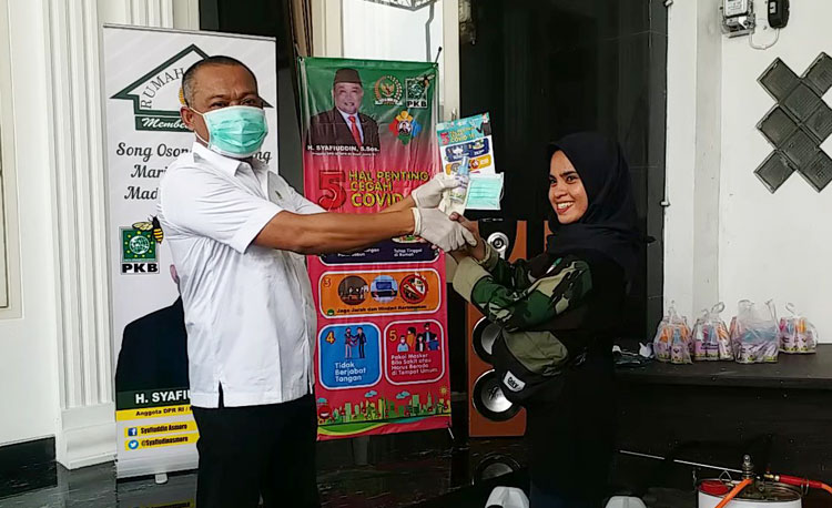 Anggota DPR RI H. Syafiuddin Asmoro saat menyerahkan masker dan hand sanitizer kepada salah satu relawan Song Osong Lombung.